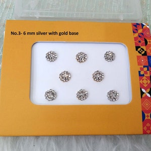Könnte beinhalten: Eine Packung mit 6 mm großen silbernen Strasssteinen mit goldener Basis. Die Strasssteine haben die Form einer Blume und sind in einem Raster auf einer gelben Karte angeordnet. Auf der Karte steht der Text "No. 3 - 6 mm silber mit goldener Basis".