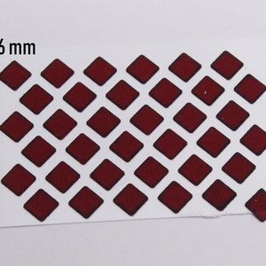 Puede incluir: Una hoja de pegatinas adhesivas de forma de diamante rojo con contornos negros. La hoja mide 6 mm de ancho.