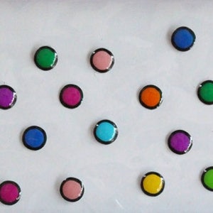 Può includere: Assortimento di adesivi rotondi colorati con contorni neri. Gli adesivi sono disposti in file su uno sfondo bianco.