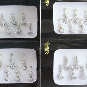 Puede incluir: Dos juegos de pegatinas decorativas plateadas y blancas para la frente o la cara. Cada juego contiene seis pegatinas con diferentes diseños.