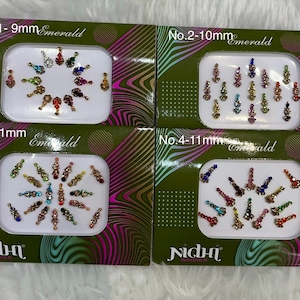 Puede incluir: Cuatro cajas de pegatinas bindi de color esmeralda, cada una con un diseño y tamaño diferente. Las cajas son verdes con un patrón ondulado y la marca "Nidhi" en blanco. Las pegatinas están dispuestas en varios patrones.