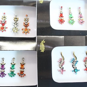 Può includere: Sei set di gioielli per il corpo decorativi, ogni set contiene tre pezzi. I gioielli sono di vari colori e design, tra cui rosso, verde, blu, arancione e argento.