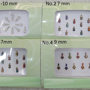 Puede incluir: Cuatro cajas de piedras de cristal de colores para el arte corporal. Cada caja contiene un tamaño y un estilo de piedras de cristal diferentes. Las cajas están etiquetadas con los números 1-10 mm, 2 7 mm, 3-7 mm y 4 9 mm.