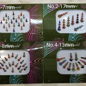 Puede incluir: Cuatro tarjetas con diferentes tamaños de piedras de cristal de colores para el arte corporal. Las tarjetas están etiquetadas con los números 1-4 y el tamaño de las piedras de cristal en milímetros. No. 1-7mm, No. 2-17mm, No. 3-8mm, No. 4-13mm.