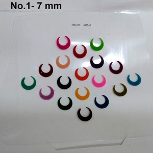 May include: A sheet of 16 crescent-shaped, self-adhesive, colourful bindi stickers. The bindi stickers are 7 mm in size and come in a variety of colours, including pink, green, blue, red, orange, and purple.