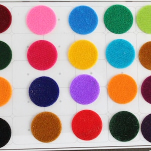 Può includere: Un set di 16 cerchi in feltro di vari colori, tra cui rosso, blu, verde, giallo, arancione, viola, marrone, nero e rosa. I cerchi sono disposti in una griglia su uno sfondo bianco.
