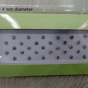 May include: A green and white box with a clear plastic window showing a sheet of small, silver, round rhinestones. The box has the text "No.1-4 mm diameter" printed on the top.