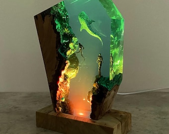 May include: A wooden base with a clear resin block containing a green and blue whale shark, coral, and divers. The resin block is illuminated from below with a warm light.
