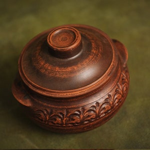 Peut inclure: Pot en céramique marron avec couvercle. Le pot présente un motif floral décoratif sur la base et une petite poignée sur le couvercle. Conçu pour la cuisine et le service, avec une esthétique rustique.