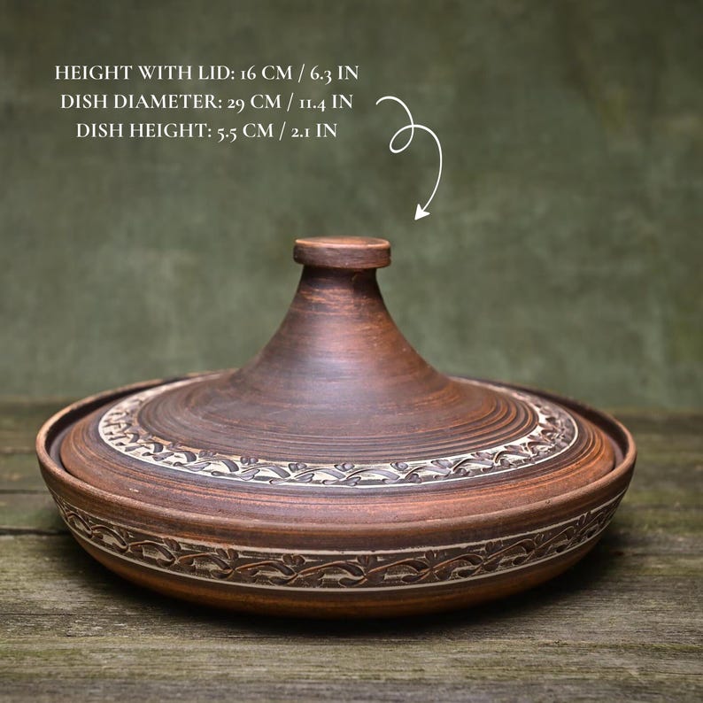 May include: A brown ceramic tagine pot with a lid. The pot is 6.3 inches tall with the lid, 11.4 inches in diameter, and 2.1 inches high. The lid and base feature decorative carved patterns. The text on the image reads: HEIGHT WITH LID: 6.3 IN, DISH DIAMETER: 11.4 IN, DISH HEIGHT: 2.1 IN.