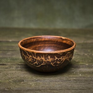 May include: A brown ceramic bowl with a decorative pattern on a wooden surface.