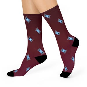 May include: Maroon socks with a repeating pattern of blue and gray spools. The socks have black heels and toes, and the spools are evenly spaced across the fabric. These socks are a fun and unique accessory.