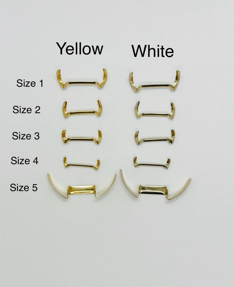 May include: Five sizes of watch band spring bars in yellow and white metal. The sizes are labeled 1 through 5.