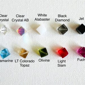 May include: Assortment of 10 square-shaped crystal beads in various colors, including clear, white, black, aquamarine, topaz, olivine, light siam, and fuchsia.