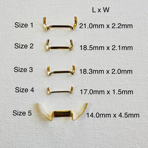 May include: Five sizes of gold metal watch band spring bars, labeled with their length and width in millimeters.  Size 1 is 21.0mm x 2.2mm, Size 2 is 18.5mm x 2.1mm, Size 3 is 18.3mm x 2.0mm, Size 4 is 17.0mm x 1.5mm, and Size 5 is 14.0mm x 4.5mm.