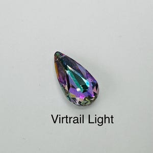 Op de afbeelding: Een druppelvormig kristal met een facetontwerp, dat een spectrum aan kleuren weergeeft, waaronder paars, groen en goud. De tekst "Virtrail Light" is eronder gedrukt. Het kristal staat tegen een witte achtergrond.