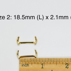 May include: Two gold-colored metal clasps, one above the other, with a ruler showing a measurement of 18.5 mm (L) x 2.1 mm (W). Size 2.