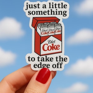 Op de afbeelding: Een sticker met een rood-witte Diet Coke-doos met zes blikjes erin. De sticker heeft de tekst "just a little something" en "to take the edge off" tegen een blauwe lucht.
