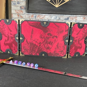 May include: A three-panel folding game screen with a red background and black and gold trim. The panels feature a demonic creature with horns and a skull-like face. The screen is designed for tabletop role-playing games.