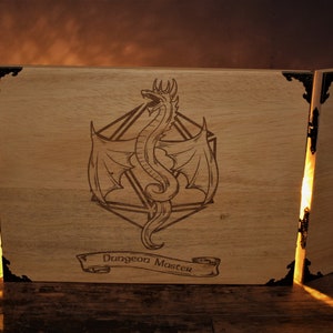 Könnte beinhalten: Ein dreiteiliger, faltbarer Bildschirm aus Holz mit einem Drachen- und einem D20-Würfel-Design. Der Bildschirm ist mit den Worten "Dungeon Master" graviert.