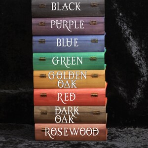 May include: A stack of eight wooden boxes with different colored finishes. The boxes are labeled with the following colors: Black, Purple, Blue, Green, Golden Oak, Red, Dark Oak, and Rosewood.