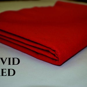 May include: A folded piece of vivid red fabric. The fabric is smooth and has a slight sheen. The text "VIVID RED" is printed below the fabric.