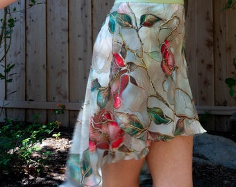 May include: A light blue leotard and a sheer, floral-print skirt. The skirt features red roses and green leaves on a cream background. The outfit is suitable for dance or artistic performances.