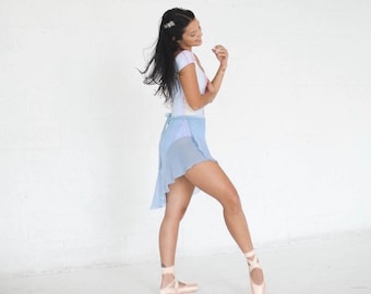 May include: A woman wearing a light blue ballet skirt and a pink and white striped leotard. She is wearing pink ballet shoes and has her hair pulled back.