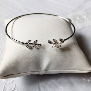 Peut inclure: Bracelet argenté avec un motif de feuilles délicates et de petites perles.