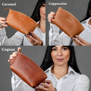 May include: Three different colored leather cosmetic bags with a zipper closure. The bags are labeled "Caramel", "Cappuccino", and "Cognac".