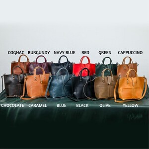 May include: Ten leather tote bags in various colors, including cognac, burgundy, navy blue, red, green, cappuccino, chocolate, caramel, blue, black, olive, and yellow. The bags are arranged in two rows, with the colors labeled below each bag.