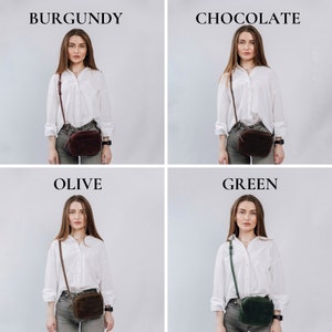 May include: Four women wearing white shirts and jeans are modeling different colored crossbody bags. The bags are burgundy, chocolate brown, olive green, and dark green.