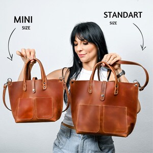 May include: Two brown leather tote bags, one labeled "MINI SIZE" and the other labeled "STANDART SIZE". The bags have a single pocket on the front and are held by a woman.