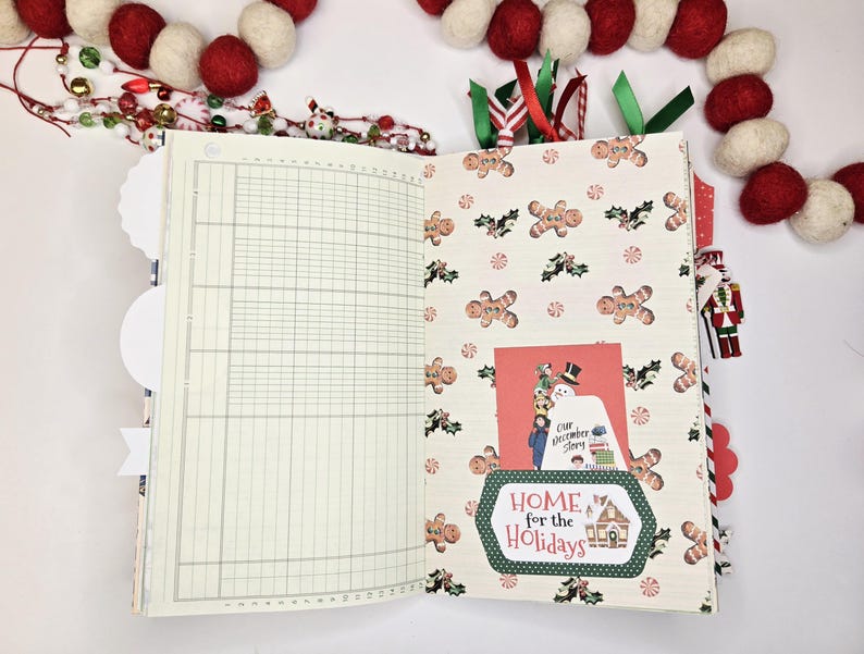 May include: Open journal with lined pages and a Christmas-themed patterned page featuring gingerbread men and holly. A card with a snowman and the text "Home for the Holidays" is tucked inside. Red and white felt ball garland in the background.