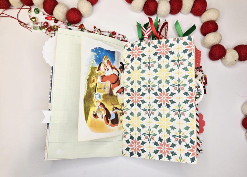May include: Open Christmas-themed journal with a Santa Claus illustration and patterned pages. The journal features a festive design with red, green, and white accents, including a decorative garland.