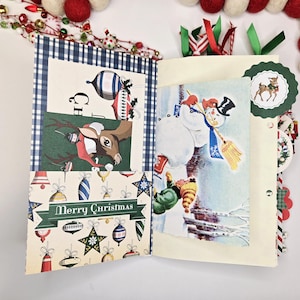 May include: Open Christmas-themed scrapbook with festive illustrations. Features a reindeer, snowman, and ornaments. The pages are decorated with ribbons and a "Merry Christmas" banner. The scrapbook is surrounded by decorative garland.