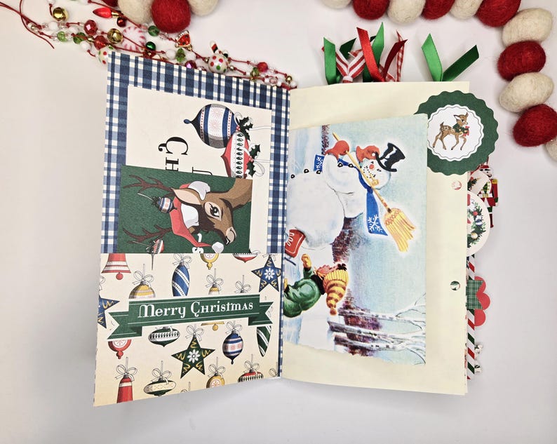 May include: Open Christmas-themed scrapbook with festive illustrations. Features a reindeer, snowman, and ornaments. The pages are decorated with ribbons and a "Merry Christmas" banner. The scrapbook is surrounded by decorative garland.