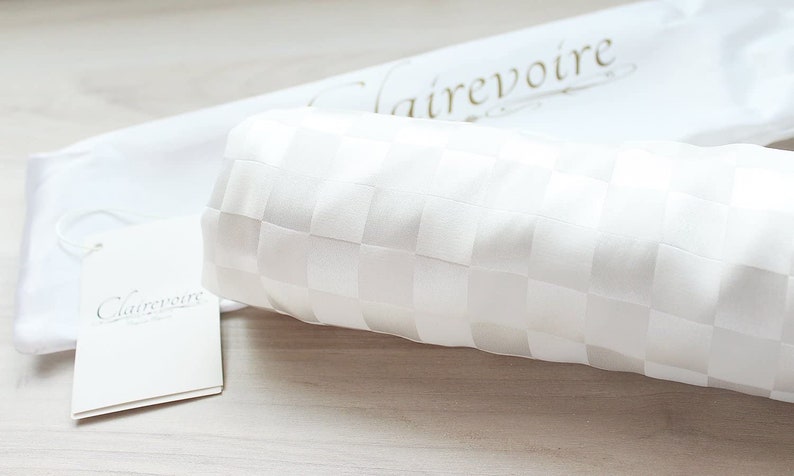 May include: White fabric with a checkered pattern, rolled up and placed on a white surface. The fabric is labeled "Clairevoire".