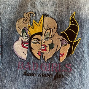 Op de afbeelding: Geborduurde patch op denim met drie gezichten van tekenfilm-schurken. De tekst "BAD GIRLS have more fun" is gestikt in paars en zwart garen. De patch is een mix van bruin, paars, zwart en geel.