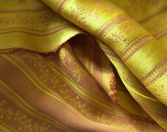 May include: Close-up of a folded fabric with a yellow and brown striped pattern. The fabric has a sheen and a floral design within the stripes. The colors are a mix of gold and a muted brown, creating a vintage aesthetic.