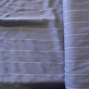 May include: A close-up of a blue and white striped fabric. The fabric is folded in half and the stripes are running vertically.