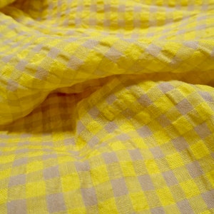 May include: Yellow and beige checkered fabric with a textured surface.