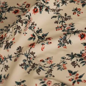 May include: White fabric with a repeating floral pattern. The flowers are red and pink with green leaves.