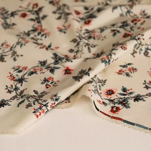 May include: Cream-colored fabric with a repeating floral pattern. The flowers are red, pink, and blue with green leaves. The fabric is folded in half and the edge is trimmed with a red and blue stripe.