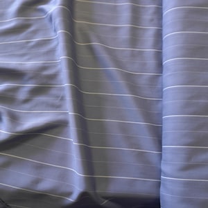 May include: A close-up of a light blue fabric with white stripes. The fabric is folded and has a smooth texture.