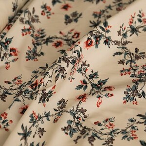 May include: White fabric with a repeating pattern of red and green floral sprigs. The fabric has a subtle sheen and a soft texture.