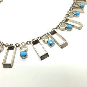 May include: Silver-toned necklace featuring rectangular and circular charms, each accented with a small, round, turquoise-colored stone. The necklace has a delicate chain and a minimalist design, suitable for everyday wear.