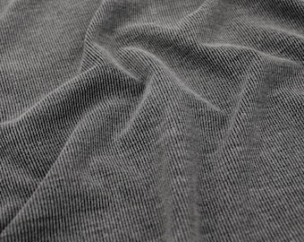 May include: Close-up of a gray ribbed fabric with a textured surface. The fabric is wrinkled and has a soft, comfortable look.