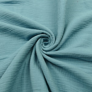 Pu&ograve; includere: Un primo piano di un tessuto morbido e blu con una texture stropicciata. Il tessuto &egrave; piegato e drappeggiato, creando uno schema a spirale.