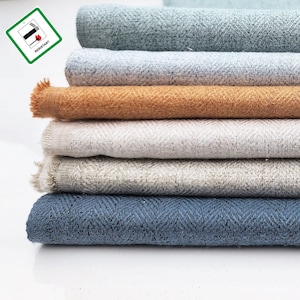 Puede incluir: Cinco muestras de tela de diferentes colores y texturas apiladas. Las muestras están dispuestas de arriba a abajo: azul claro, blanco, naranja, beige y azul oscuro. Todas las muestras están tejidas con un patrón de espiga.